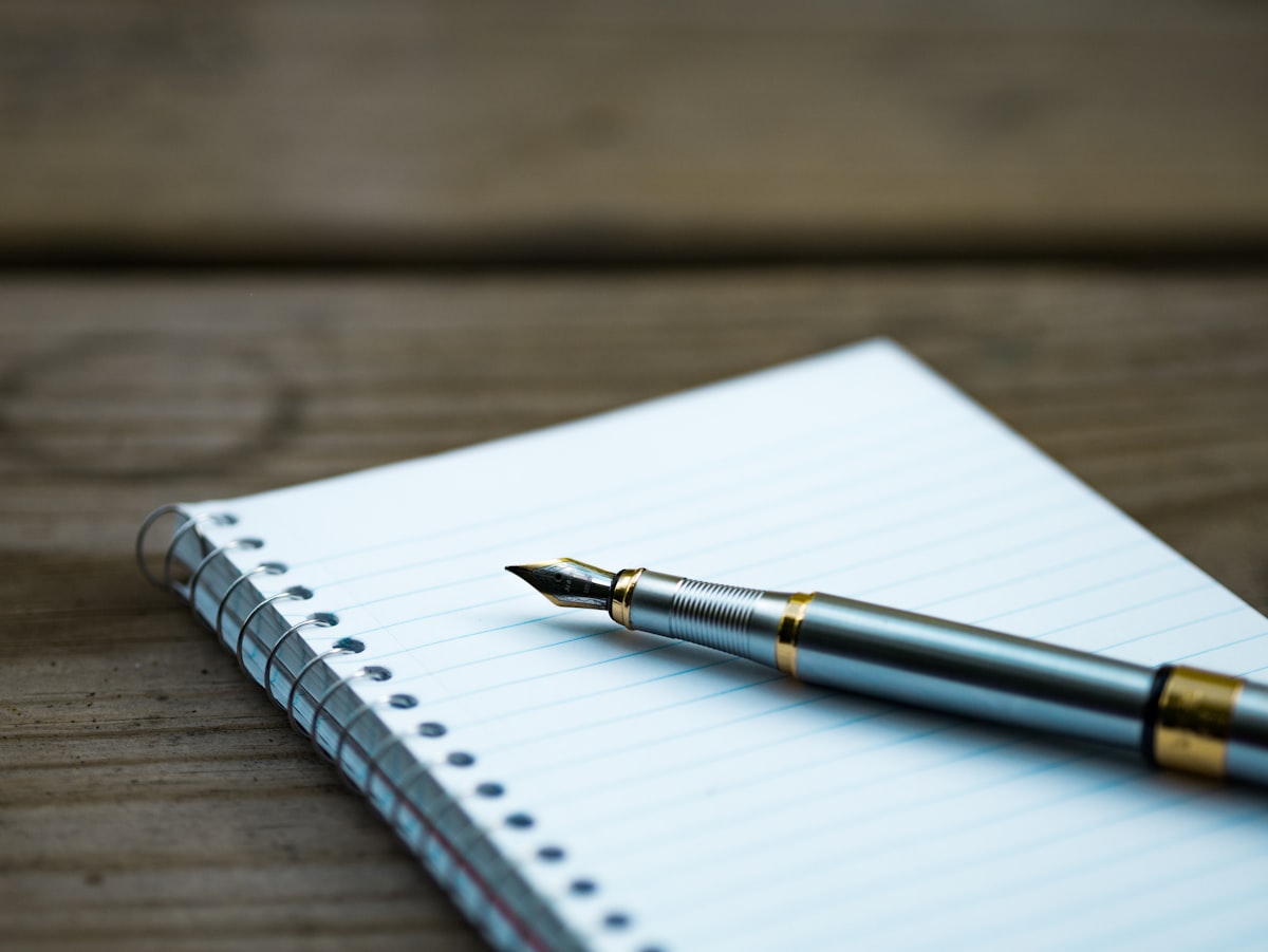 A fountain pen resting on an open spiral notebook, ready for creative writing
