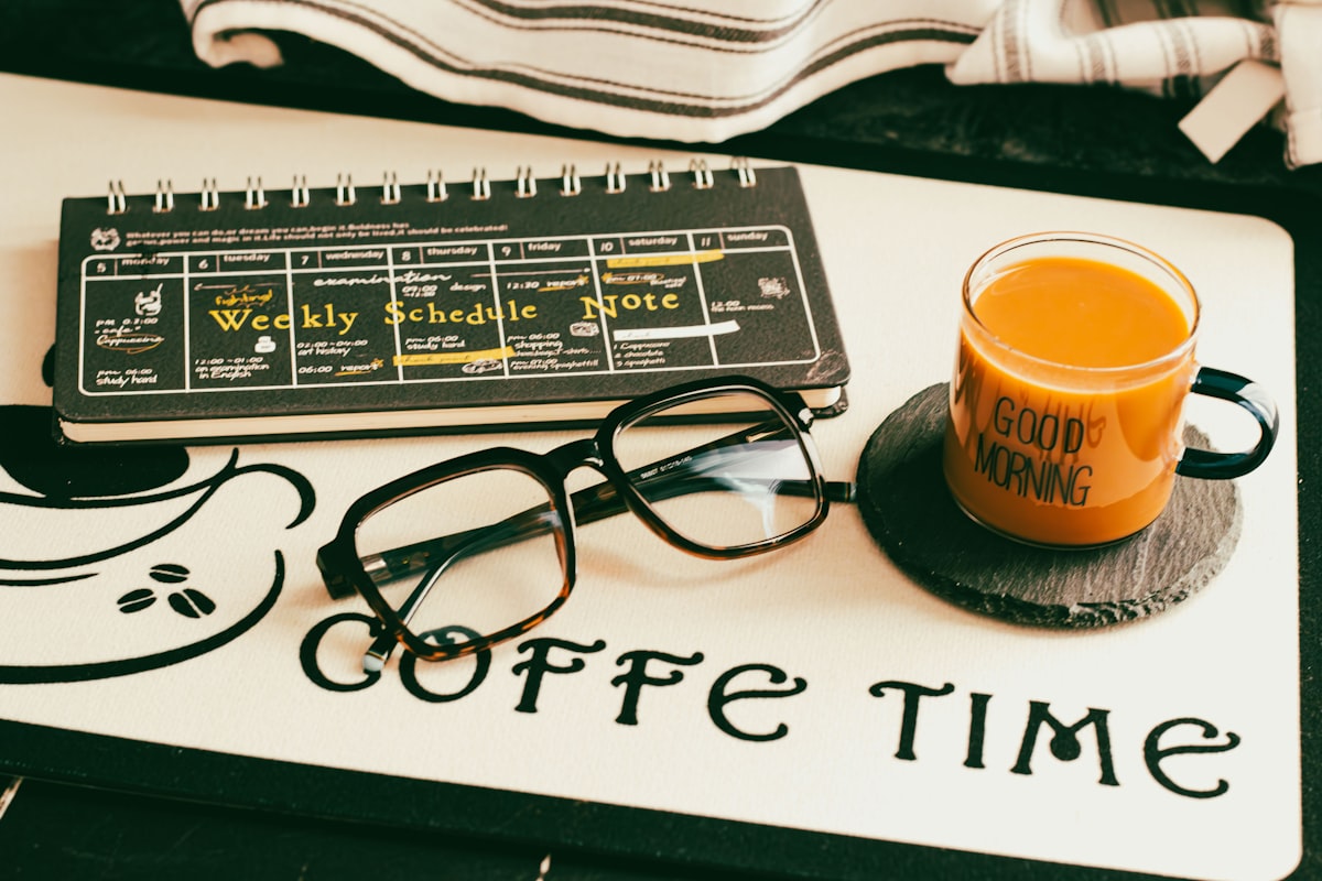 Glasses, coffee mug, and planner on a morning desk
