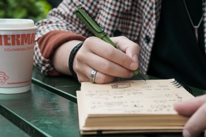 An open notebook with handwritten text on a wooden desk with morning light