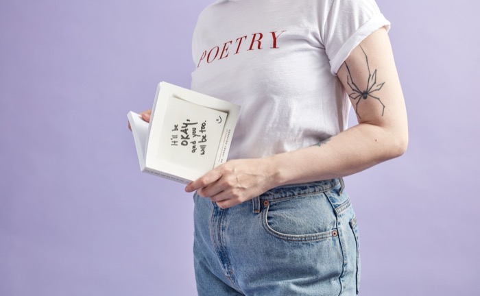 An open notebook with handwritten poetry and a pen on a wooden desk